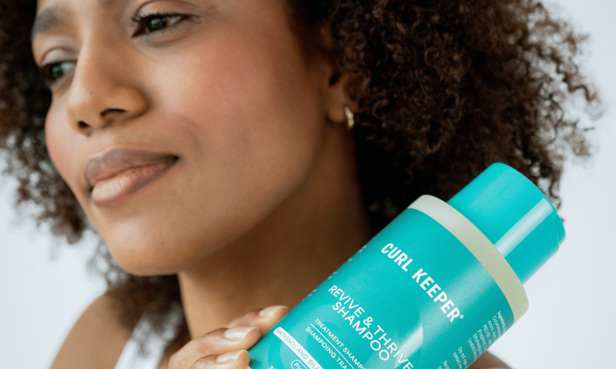Woman With Curly Hair holding curl keepers revive & thrive shampoo