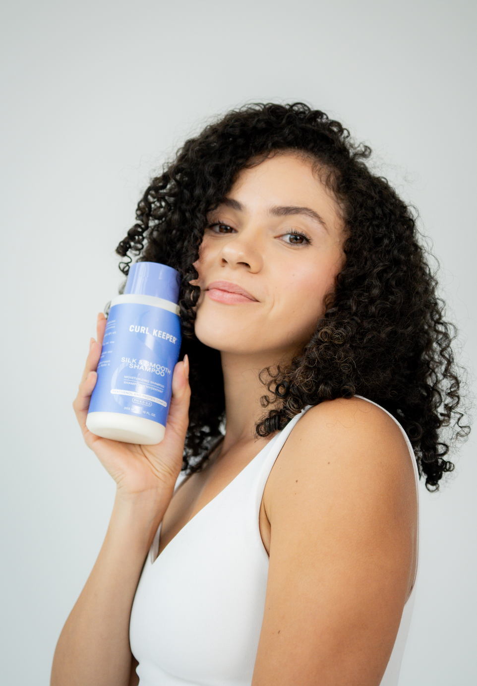 Curly Woman holding Curl Keepers Silk & Smooth Conditioner